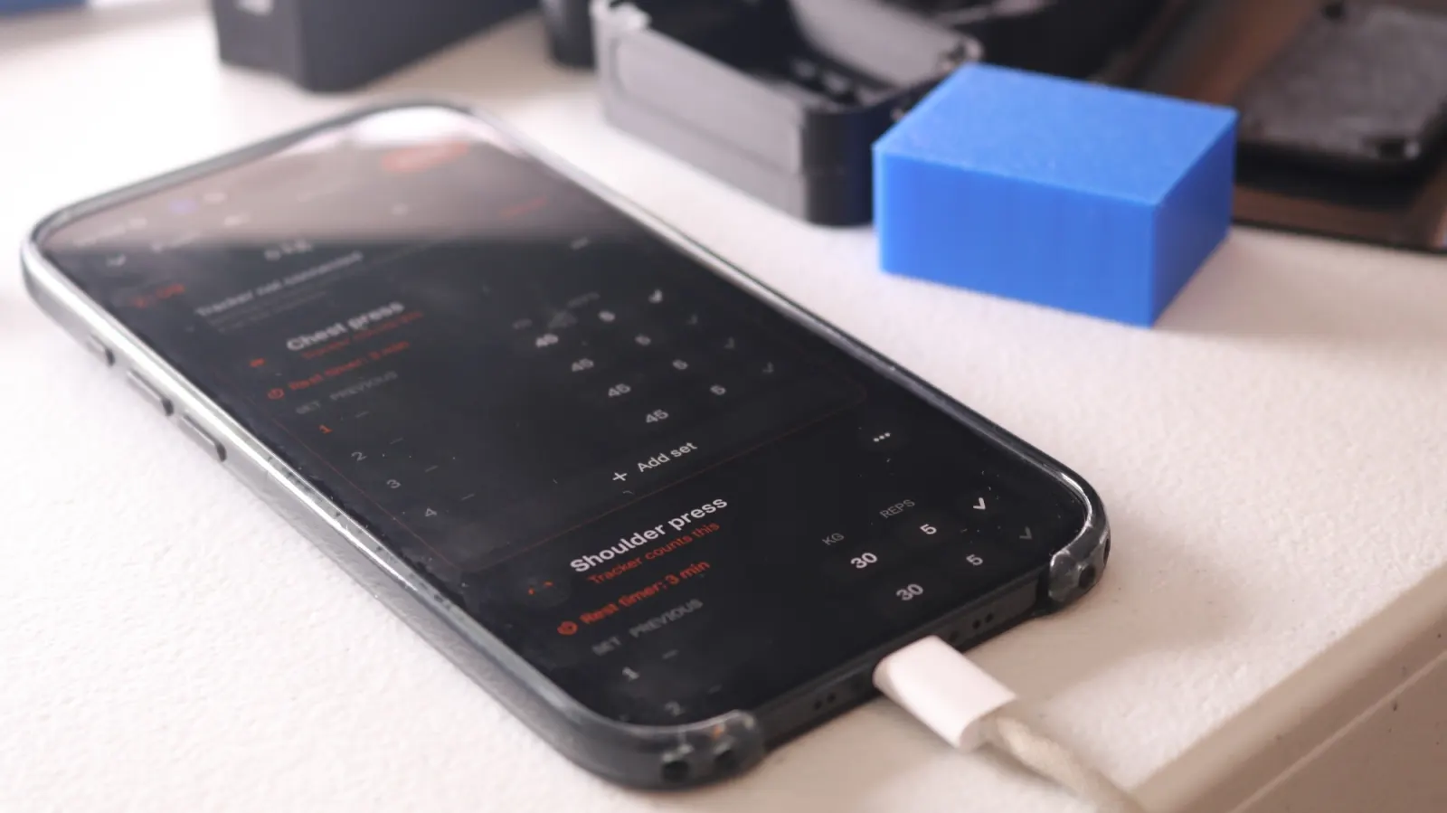 The NOMAE app on an iPhone mid-workout, showing chest press and shoulder press sets.